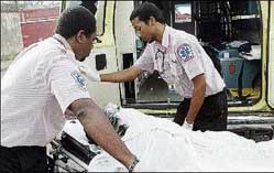 Emergency medical technicians prepare to carry away a fire victim from the Cool Petroleum Ltd fuel depot on Sunday. - Rudolph Brown/Chief Photographer. emtechnicians